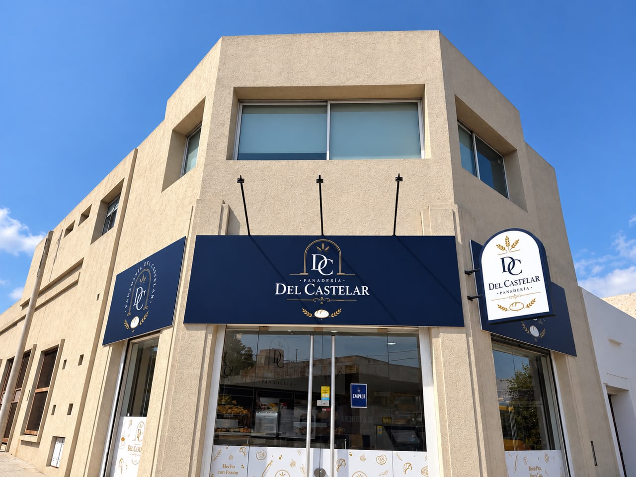 La esquina y entrada de Del Castelar Panadería, con su cartelería azul y dorada